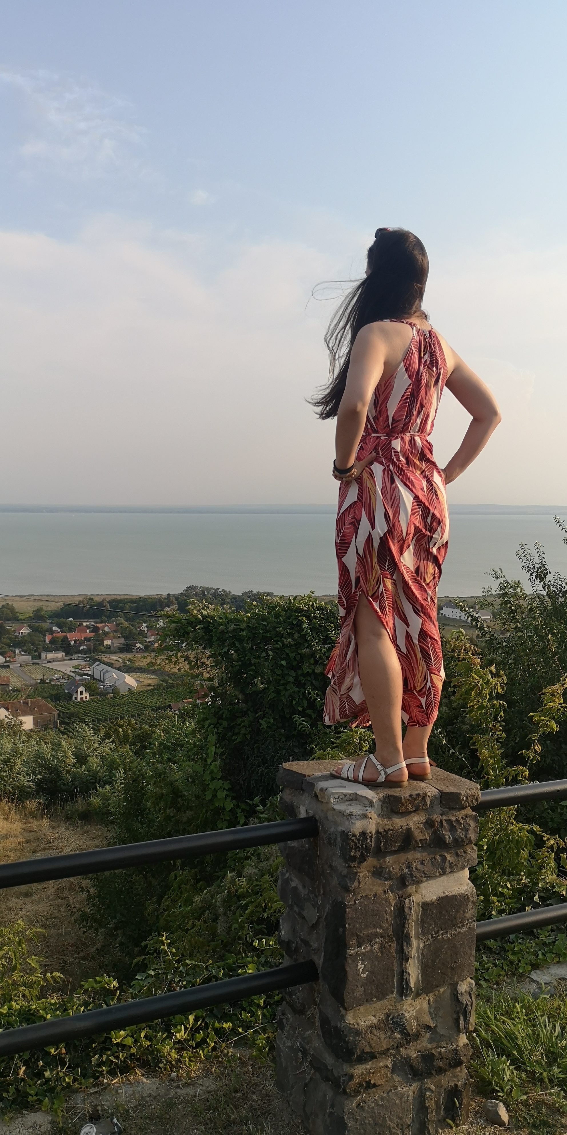 a girl on a column looking at a seascape