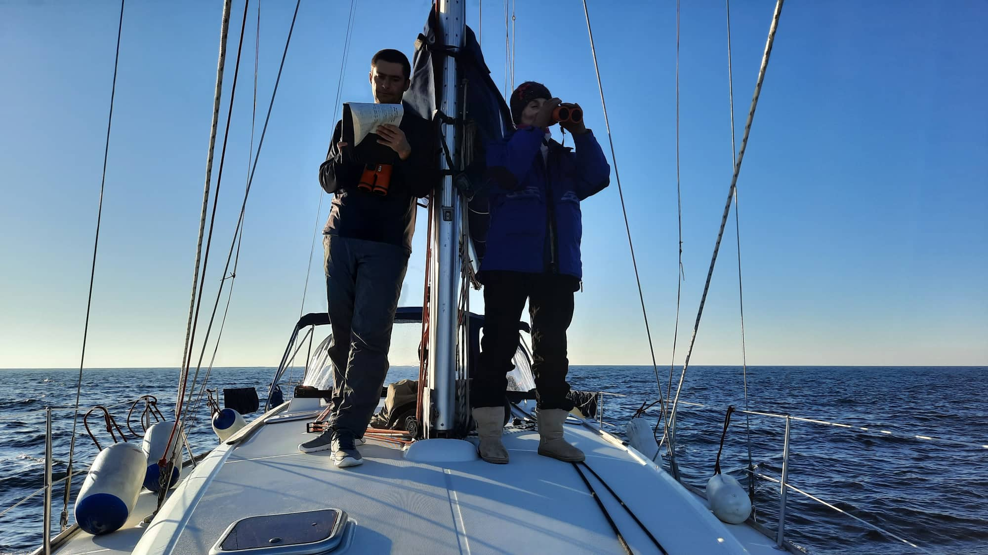 two researchers on a boat observing the sea with binoculars